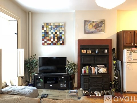 A living room with a television, a bookshelf, and a painting on the wall.