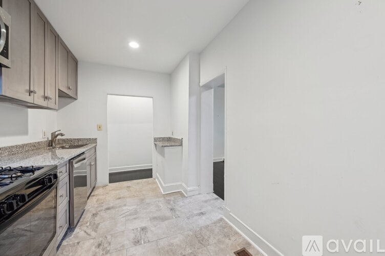 A kitchen with a black stove top oven and a marble floor.