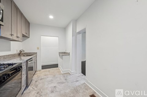 A kitchen with a black stove top oven and a marble floor.