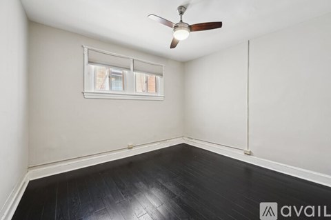 A spacious room with wooden floors and a large window with curtains.