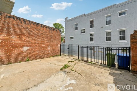 A backyard with a brick wall and a metal fence.