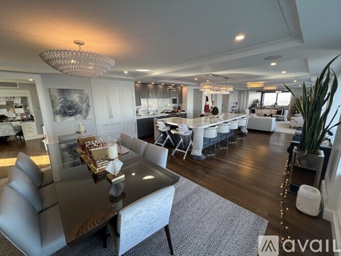 A modern living room with a glass table and grey chairs.