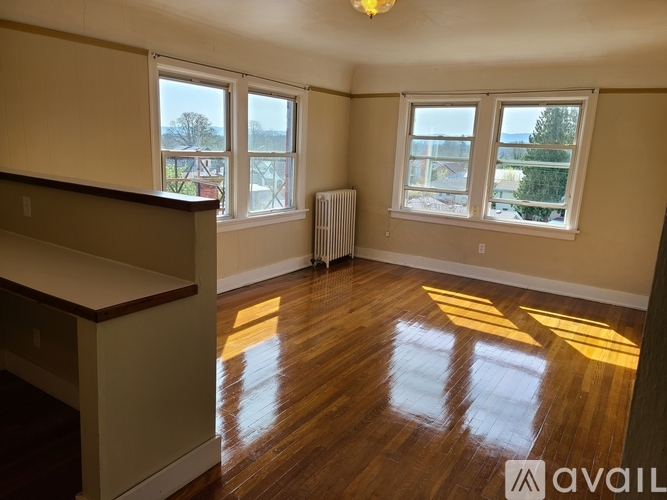 A room with wooden floors and three windows.