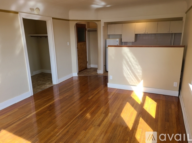 A room with wooden floors and white walls is available for rent.