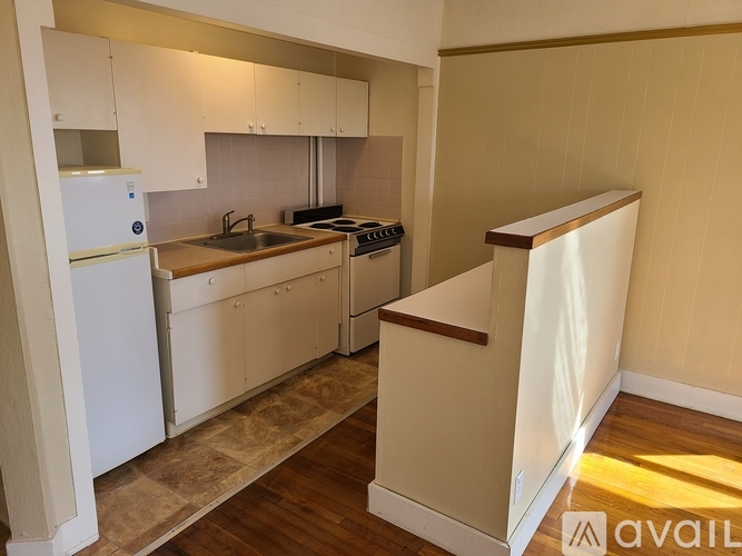A kitchen with white cabinets and a wooden floor.