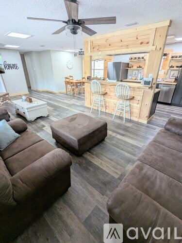 A living room with a brown couch and a wooden bar area.