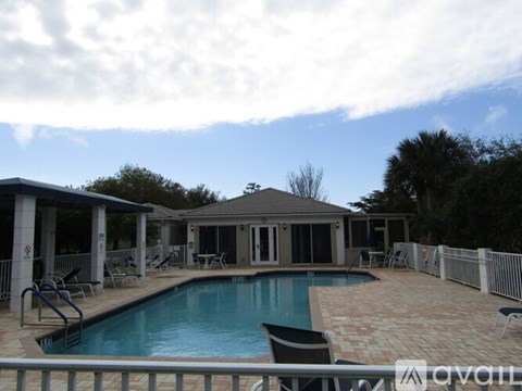 A pool with a small pavilion and chairs around it.