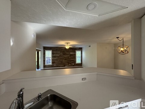 A kitchen with a stainless steel sink and a window with a brick wall.