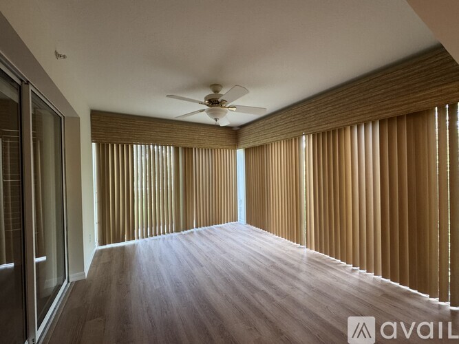 A spacious room with a ceiling fan and sliding glass doors leading to a garden.