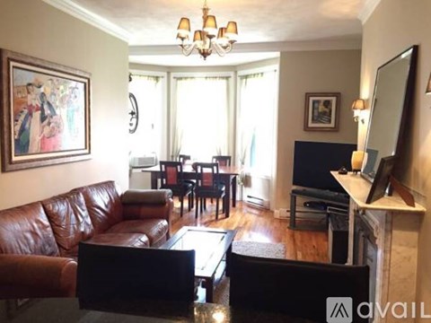A living room with a brown leather couch and a fireplace.