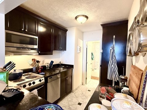 A kitchen with black cabinets and a stove top oven.