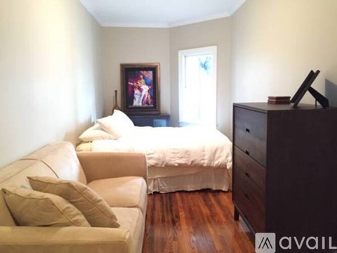 A bedroom with a bed, a couch, and a painting on the wall.