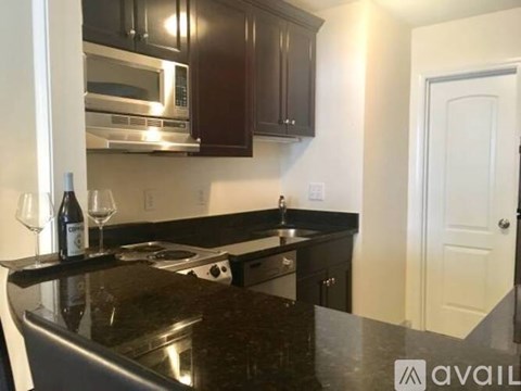 A kitchen with dark brown cabinets and a black countertop.