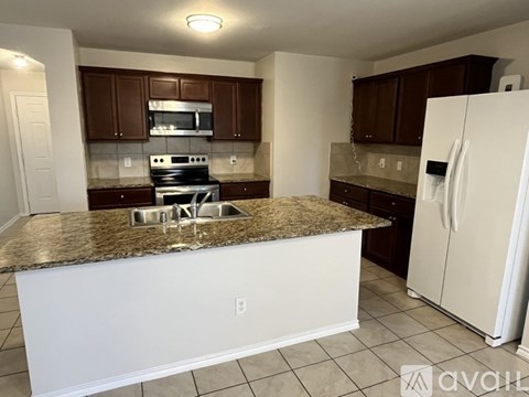 A kitchen with brown cabinets and a granite countertop.