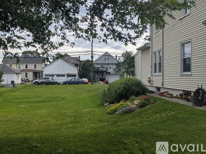 A grassy area with a house and a car in the background.