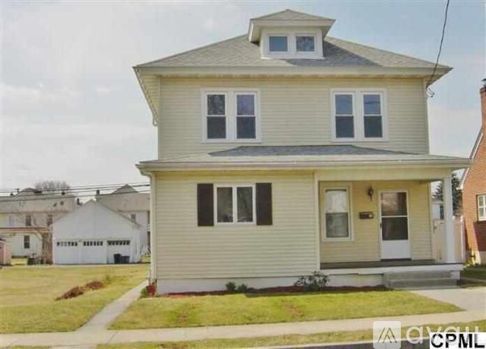 A two-story house with a front porch and a small front yard.