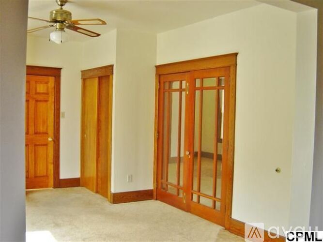 A room with a ceiling fan and a door.