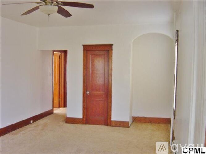 A room with a ceiling fan and two doors.