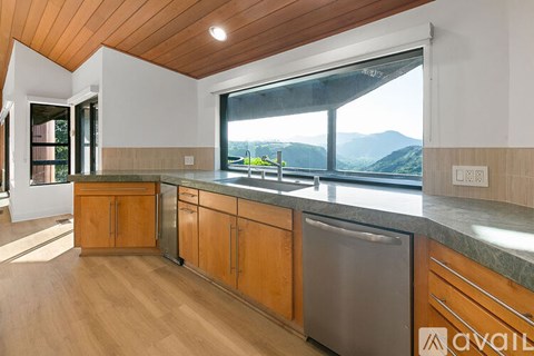 A kitchen with wooden cabinets and a large window overlooking the mountains.