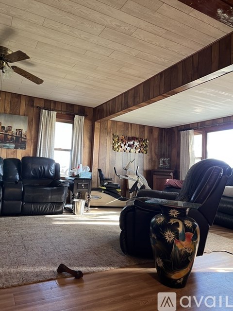A living room with a black leather sofa and a wooden ceiling.