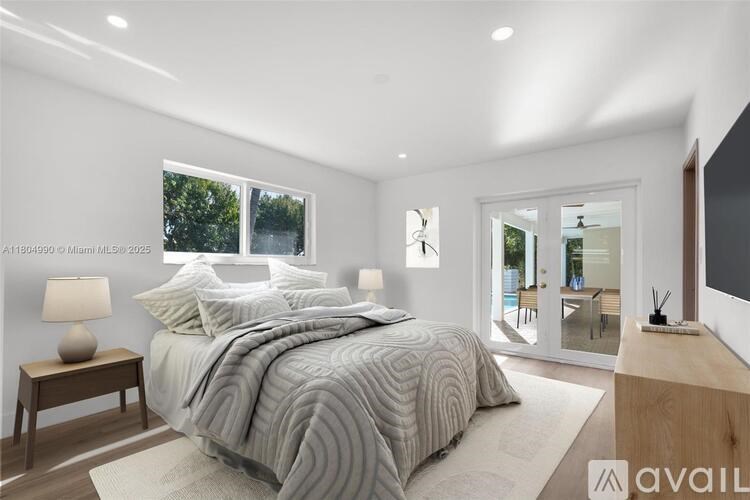 A bedroom with a large bed and a window overlooking a pool.