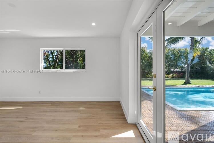 A room with a wooden floor and a large window overlooking a pool.