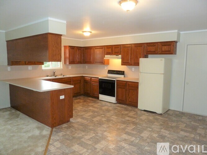 A kitchen with brown cabinets and a white refrigerator.
