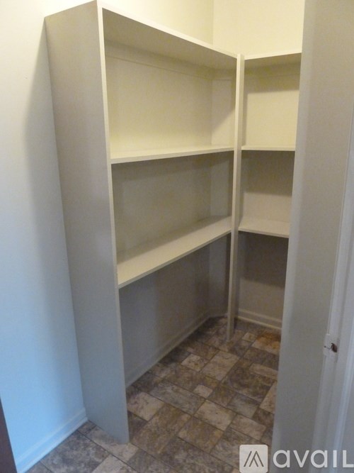 A white closet with shelves and a tiled floor.