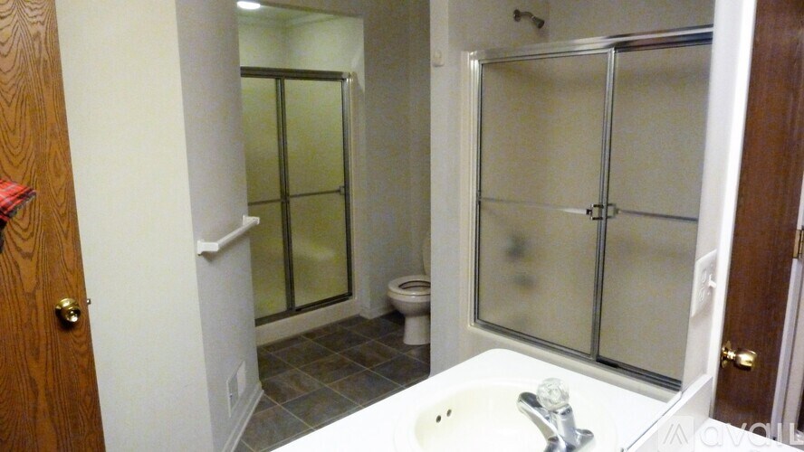 A white sink is in a small bathroom with a walk-in shower.