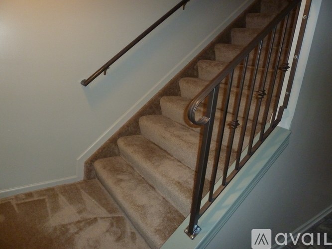 A staircase with a metal railing and beige carpeted steps.