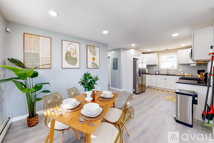 A dining area with a table set for four and a kitchen in the background.