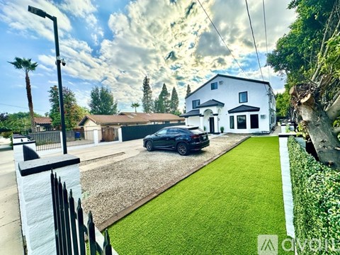 A black car is parked in front of a white house.
