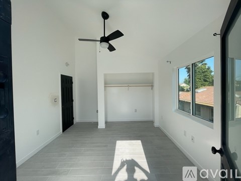 A spacious room with a ceiling fan and a large window.