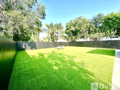 A backyard with a green lawn and a wooden fence.