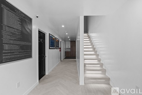 A long hallway with a staircase and a black board on the wall.