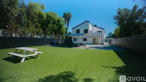 A house with a white fence and a green lawn in front.