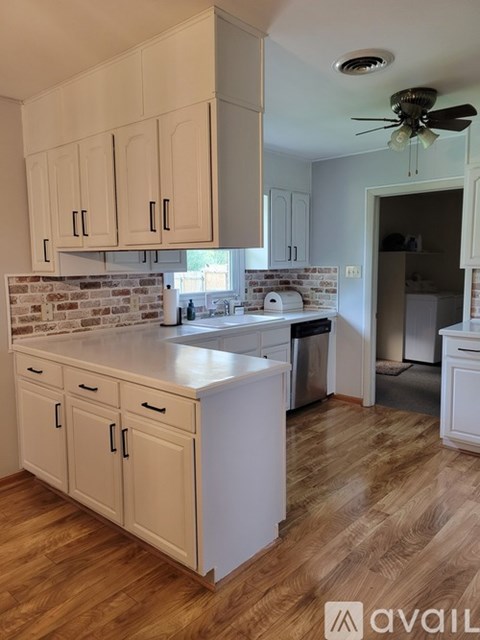 A kitchen with white cabinets and a brick backsplash.