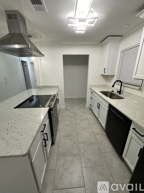 A kitchen with white cabinets and a marble countertop.