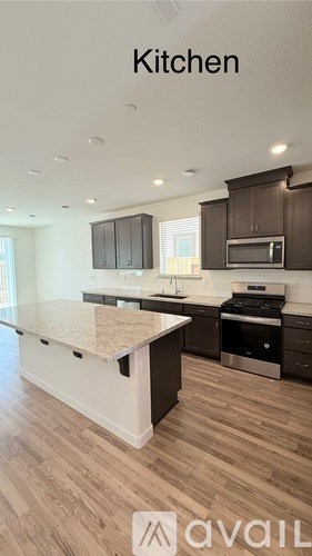 A modern kitchen with dark brown cabinets and a white island.
