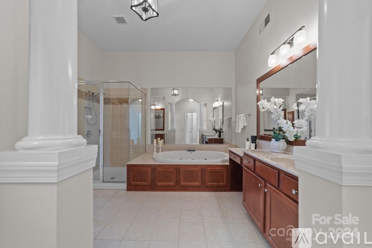 A spacious bathroom with a large mirror, double sinks, and a walk-in shower.