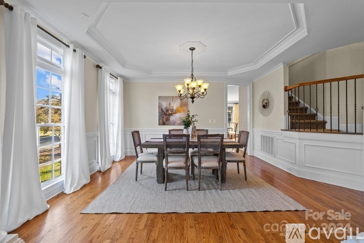 A dining room with a table set for six and a chandelier hanging from the ceiling.