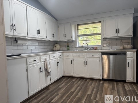 A kitchen with white cabinets and a wooden floor.