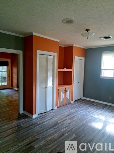 A room with wooden floors and a window with blinds.