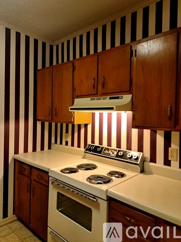 A kitchen with striped wallpaper and wooden cabinets.