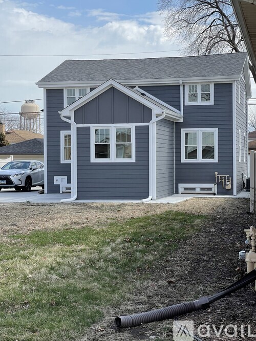 A grey house with a white car parked in front.