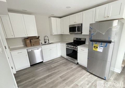 A kitchen with white cabinets and a grey fridge.