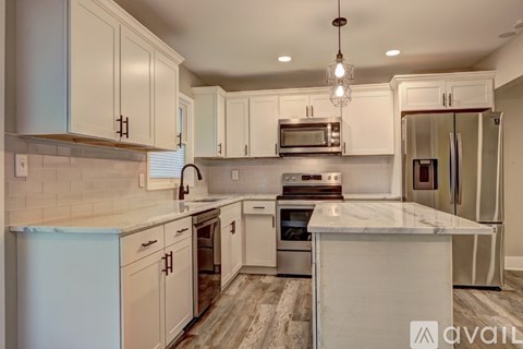 A kitchen with white cabinets and a marble countertop.