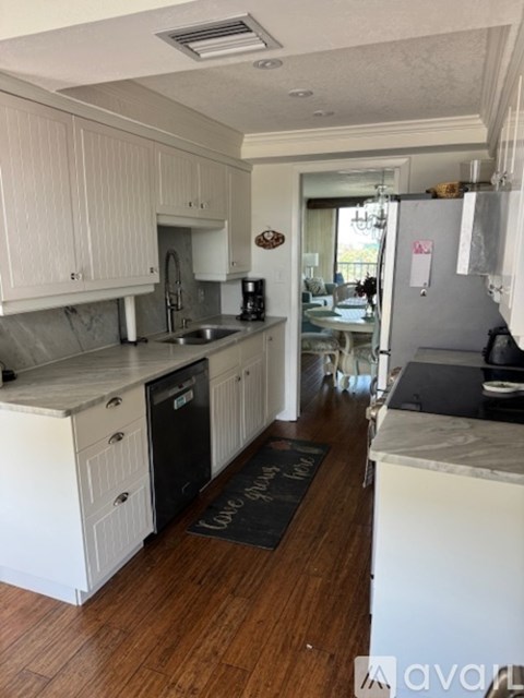 A kitchen with white cabinets and a black fridge.