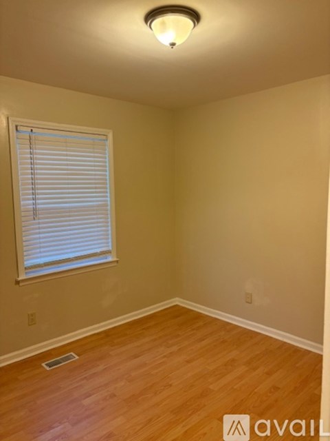 A room with wooden flooring and a window with blinds.