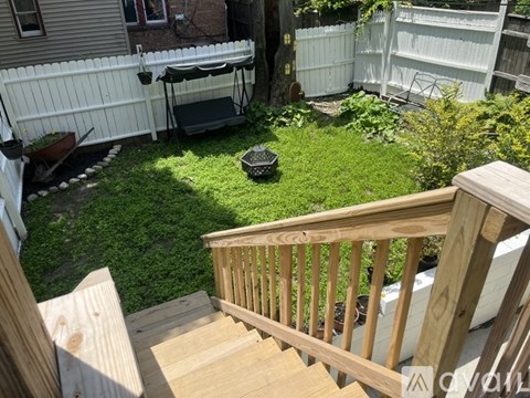 A garden with a variety of plants in pots and a tree stump in the background.
